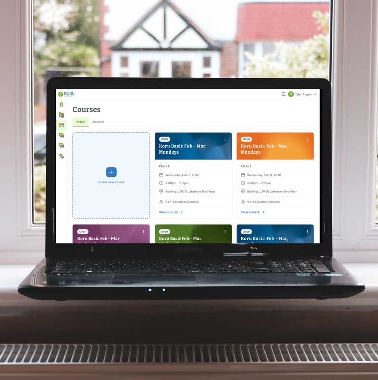 A laptop computer on windowsill in front of a window. Screen on laptop shows a list of courses on the Koru Teacher Dashboard.