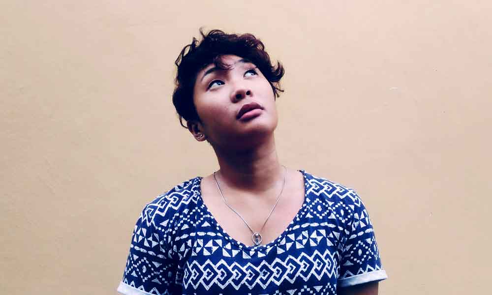 Picture of a woman looking up thoughtfully on plain background.