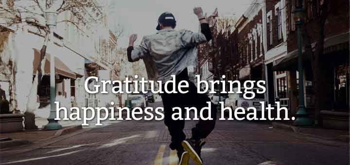 A picture of a young man of color jumping happily with arms up in the middle of a street in the city.